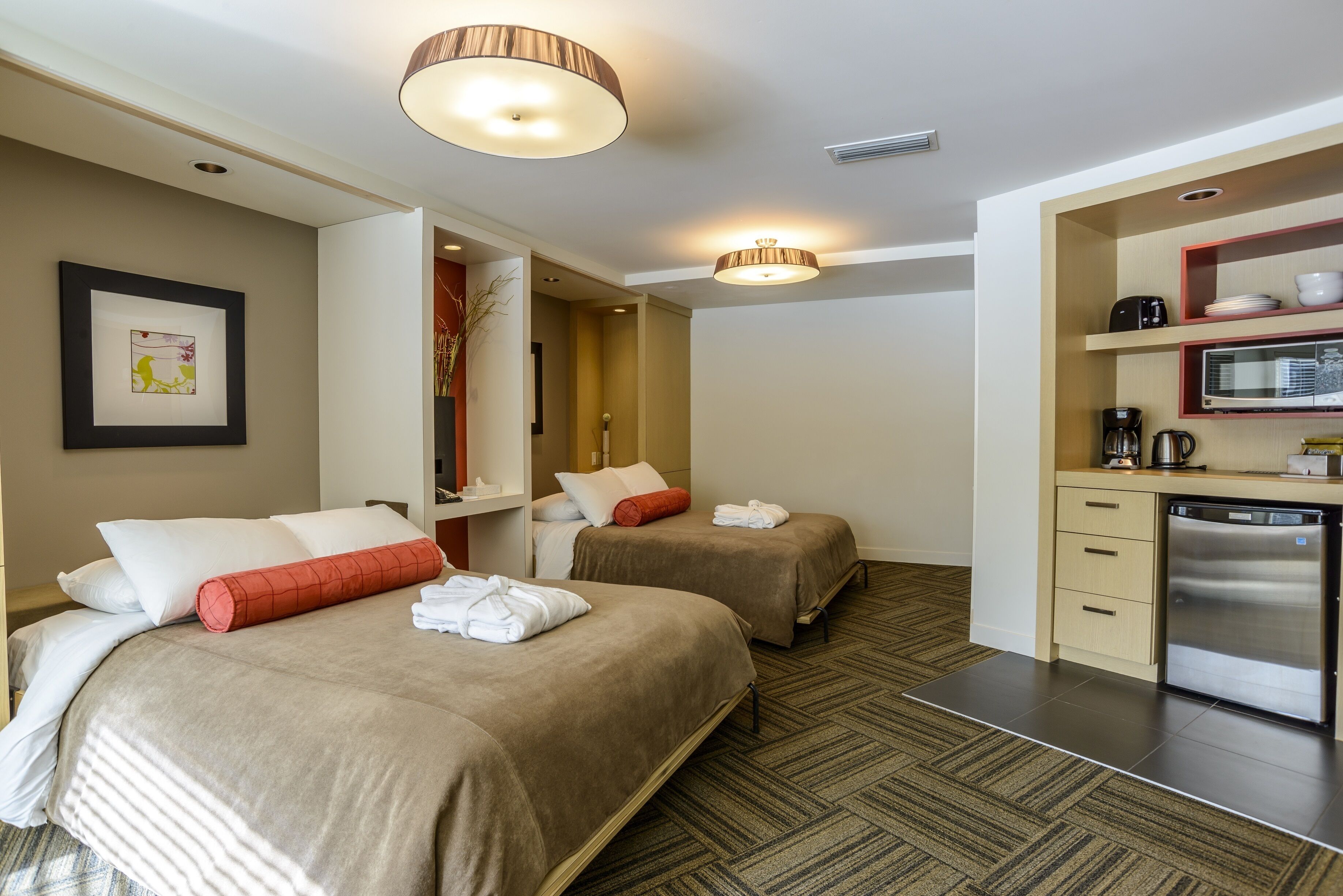 Una habitación de hotel con dos camas, kitchenette y baño.