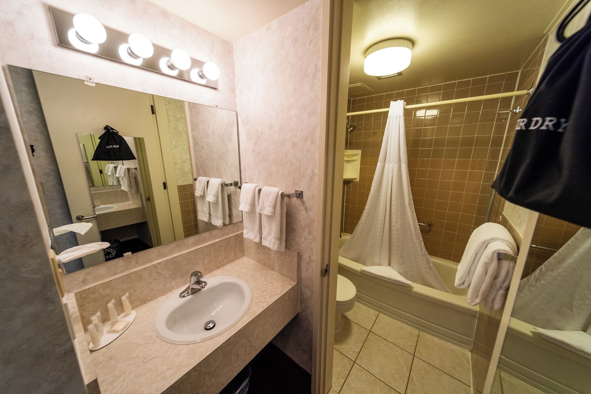 Une salle de bain avec un lavabo, un miroir et un rideau de douche.