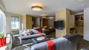 Une chambre d’hôtel moderne équipée d’un canapé, d’un téléviseur à écran plat, d’un petit coin cuisine et d’une table à manger.
