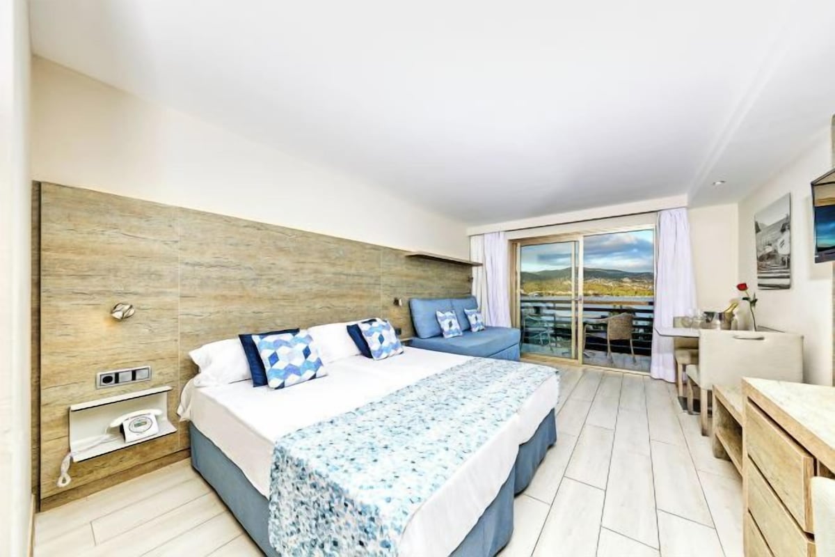 Une chambre d’hôtel moderne avec un grand lit, un bureau et un balcon offrant une vue agréable.