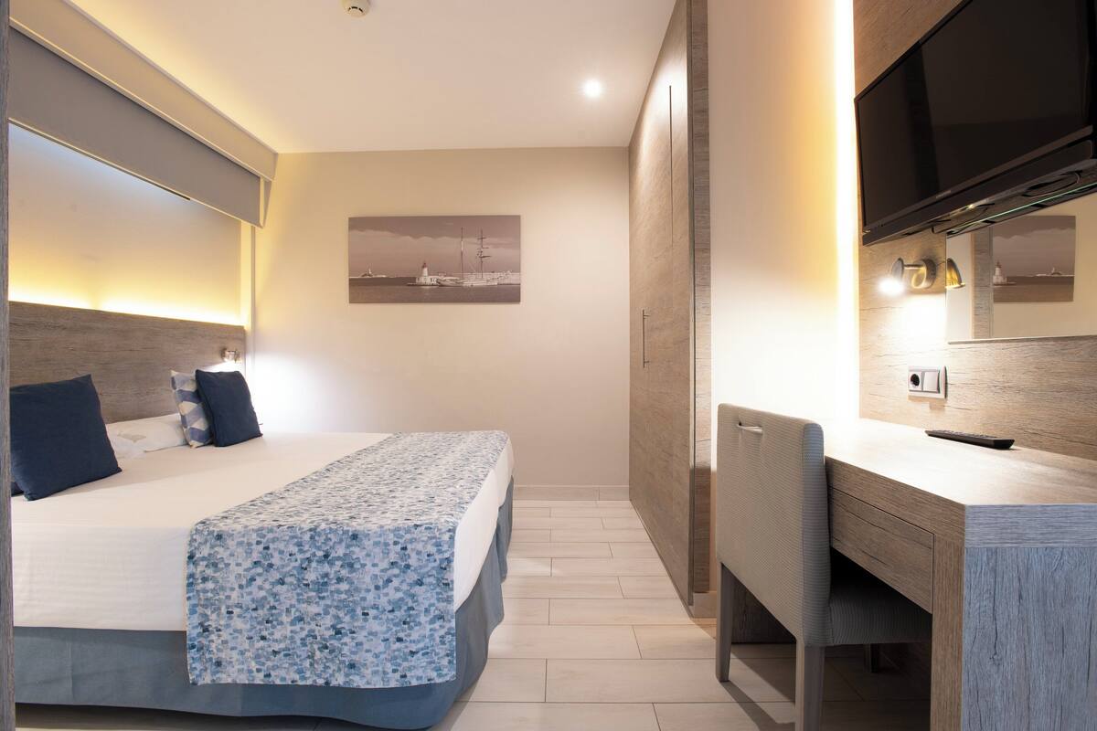 Moderni hotellihuone, jossa on sänky, työpöytä ja suuri peili.