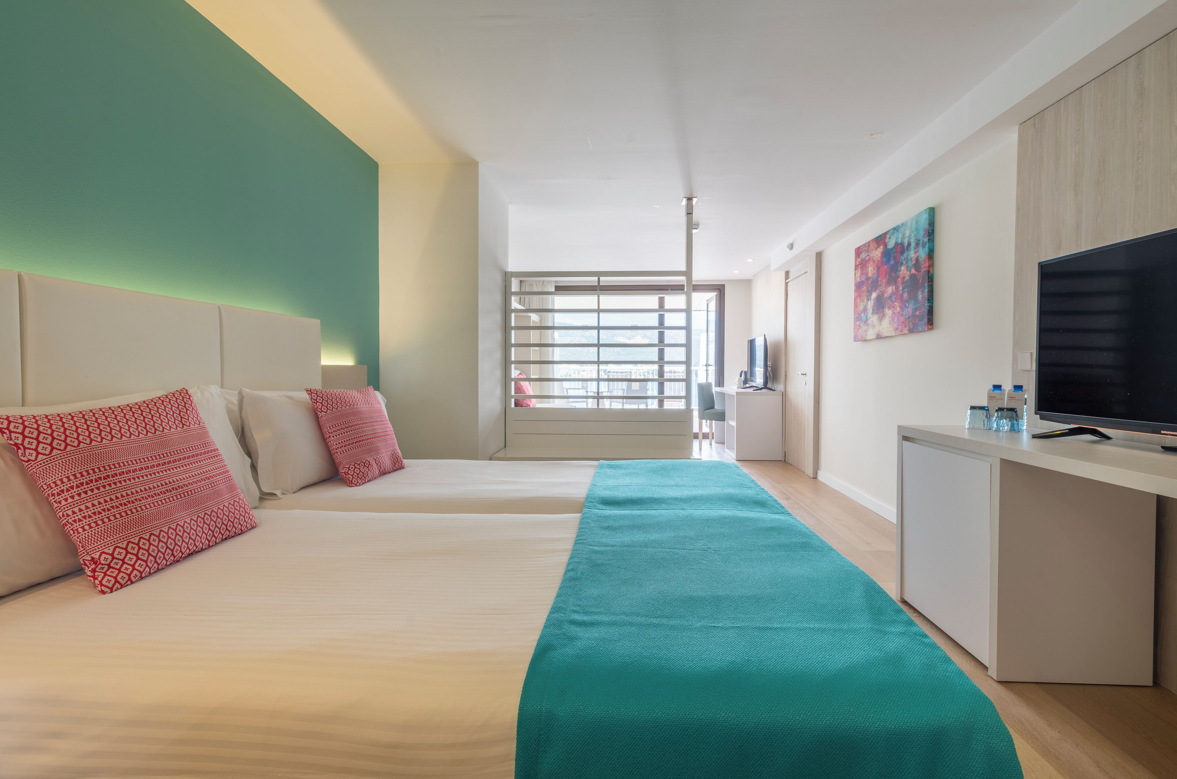 Une chambre d’hôtel avec deux lits, un bureau, une télévision et une fenêtre donnant sur la ville.