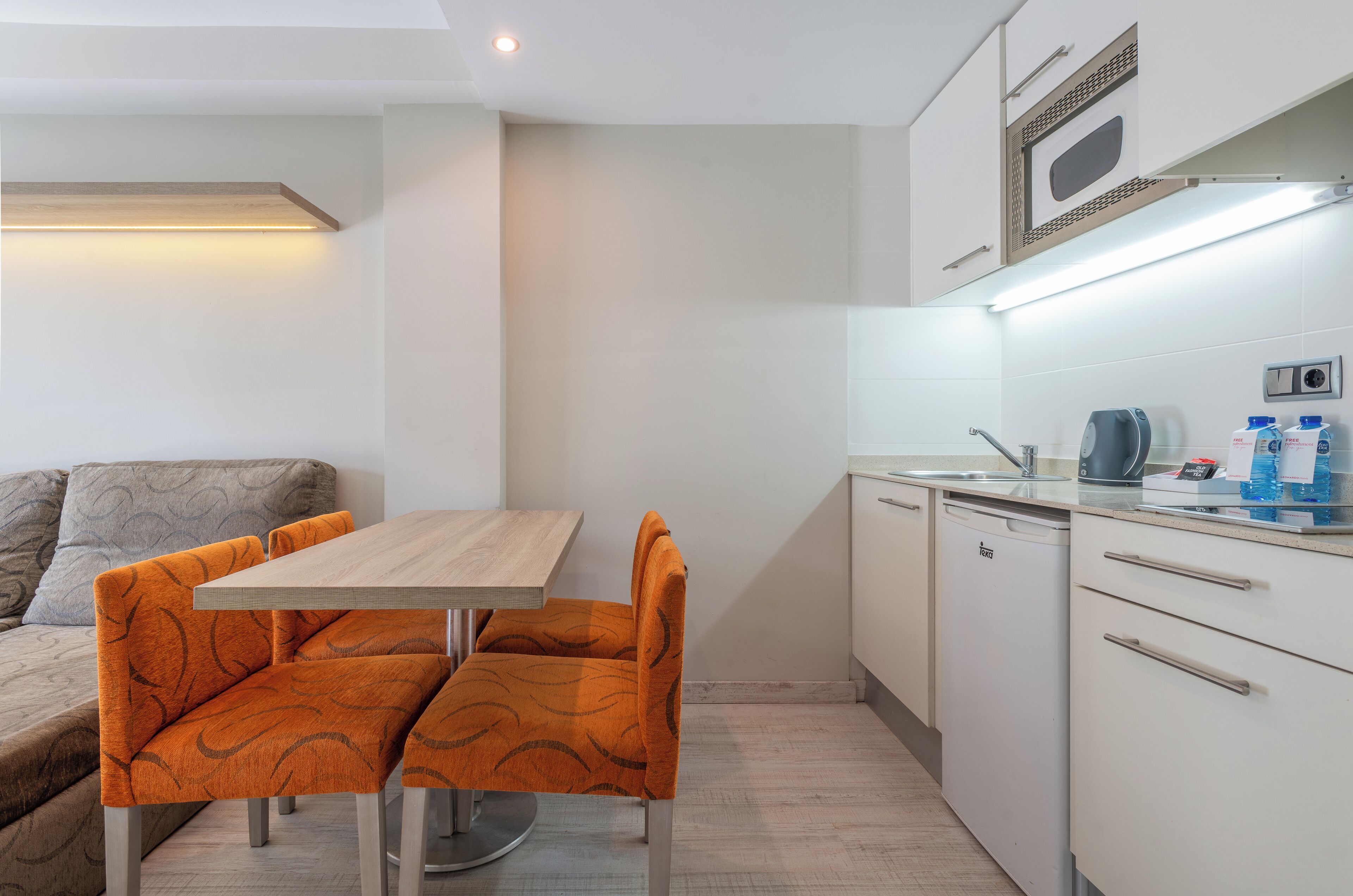 Una kitchenette compacta con microondas, pileta y encimera.