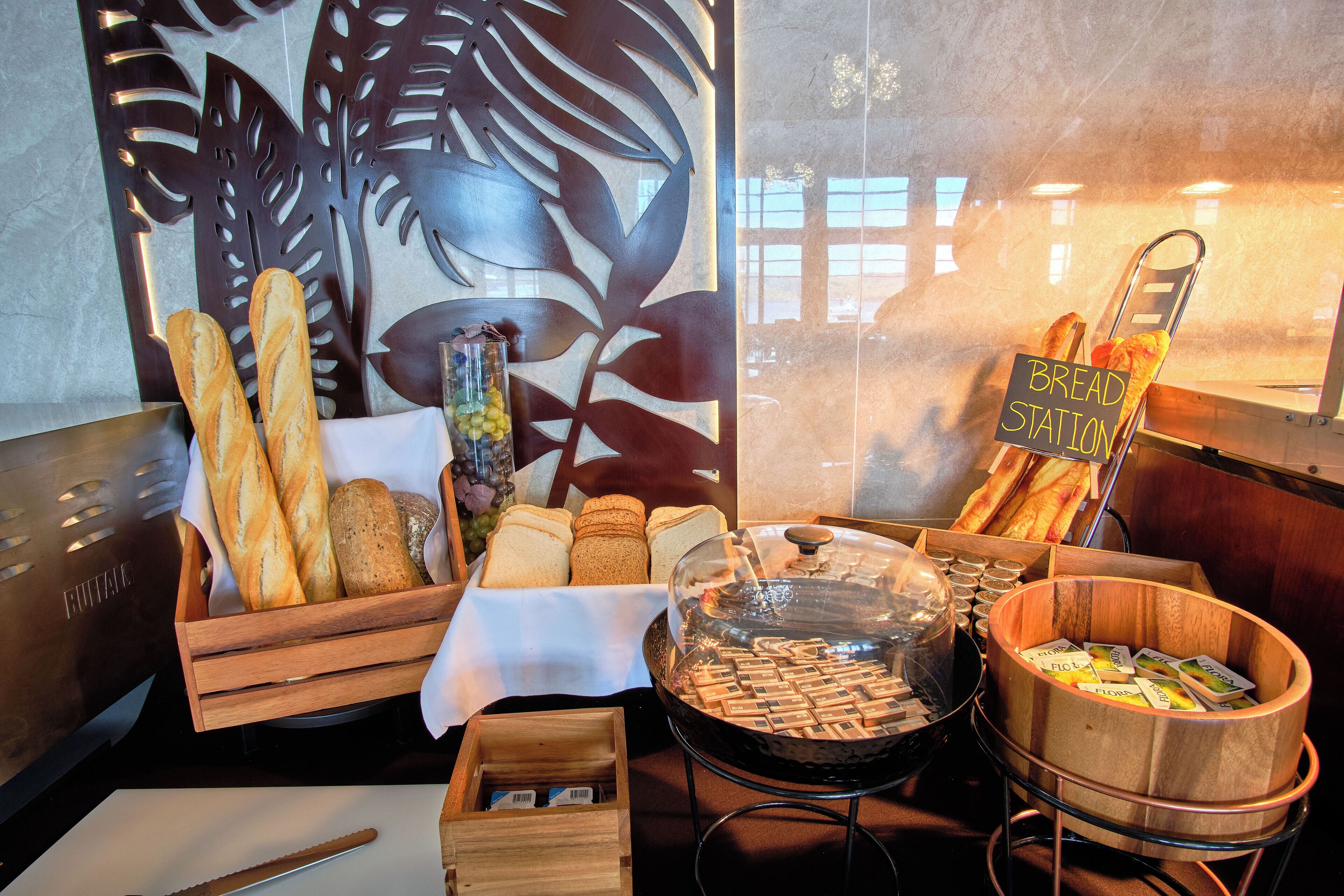 A bakery display with various breads and pastries, a sign reading "BREAD STATION," and a wooden bread box.