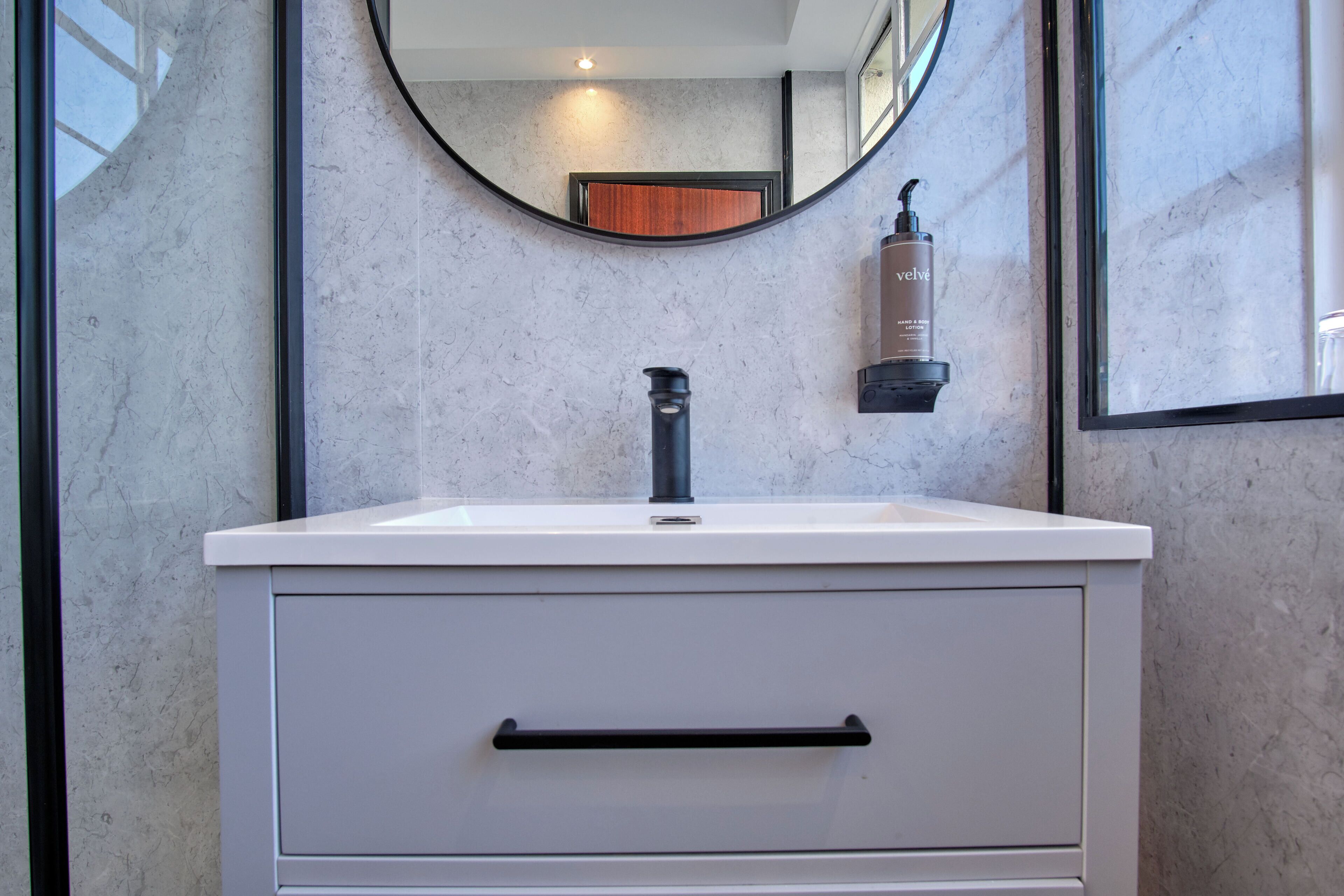 A bathroom with a white vanity, a black faucet, and a mirror above the sink.