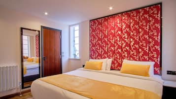Una habitación de hotel con una cama grande, un cabecero floral rojo y vistas al pasillo.