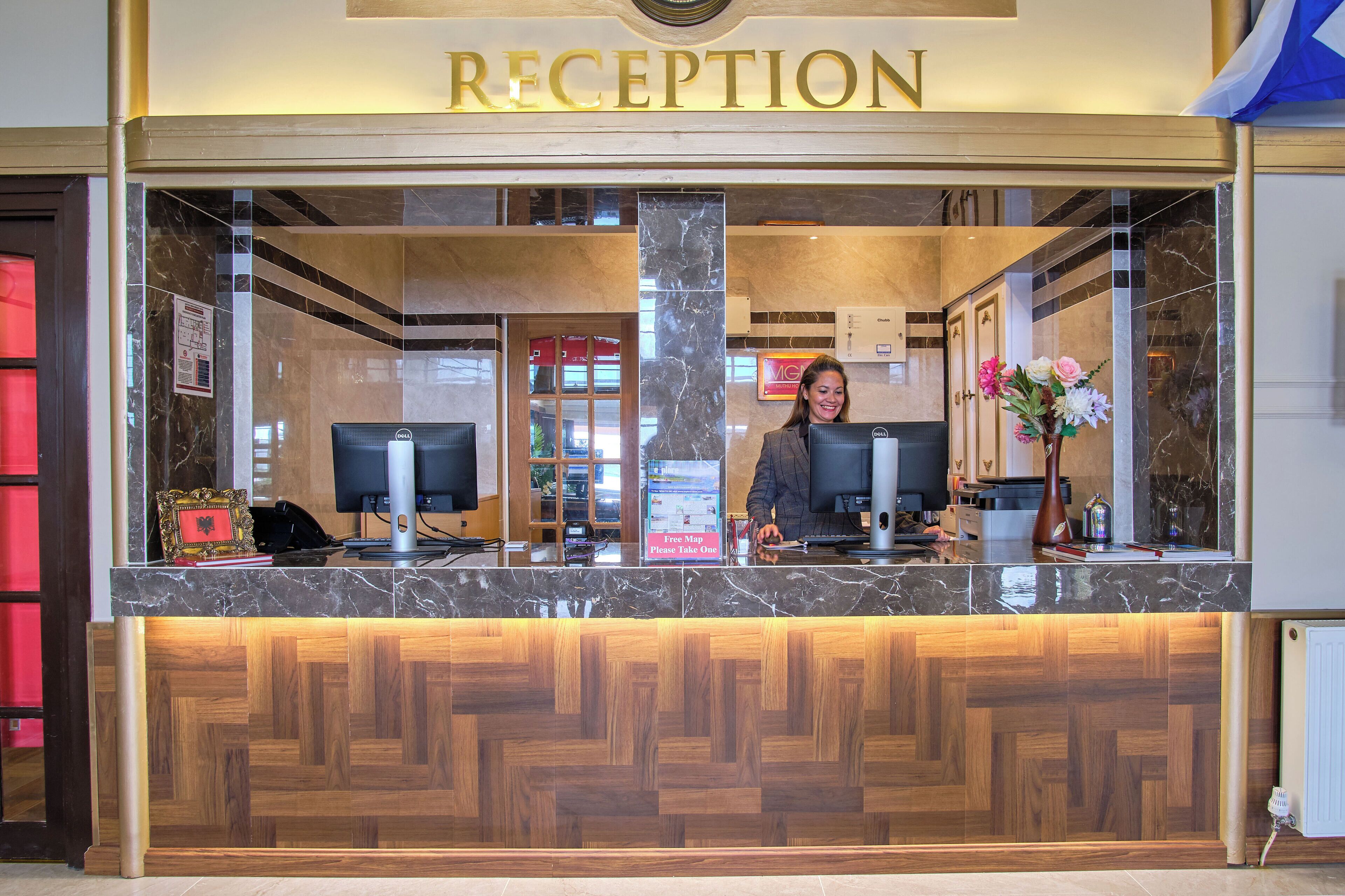A reception desk with a marble top, a wooden lower section, and a sign above that reads "RECEPTION".