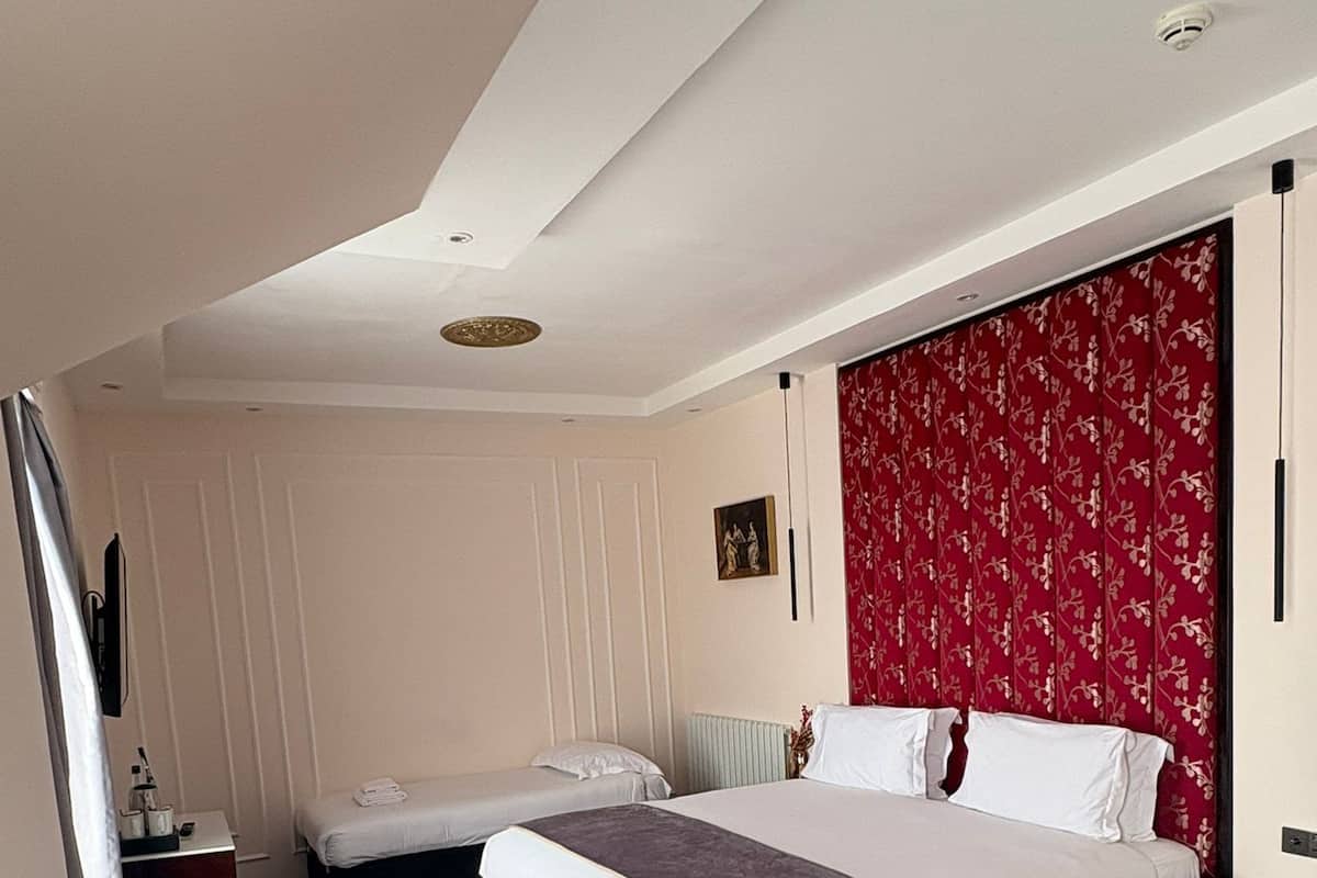 A modern bedroom with a large bed, a smaller bed, a desk, and a chair.