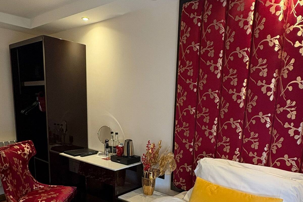 A hotel room with a bed, a desk, a chair, and a wardrobe.