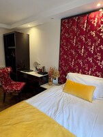 Una habitación de hotel con una cama, un escritorio, una silla y un armario.