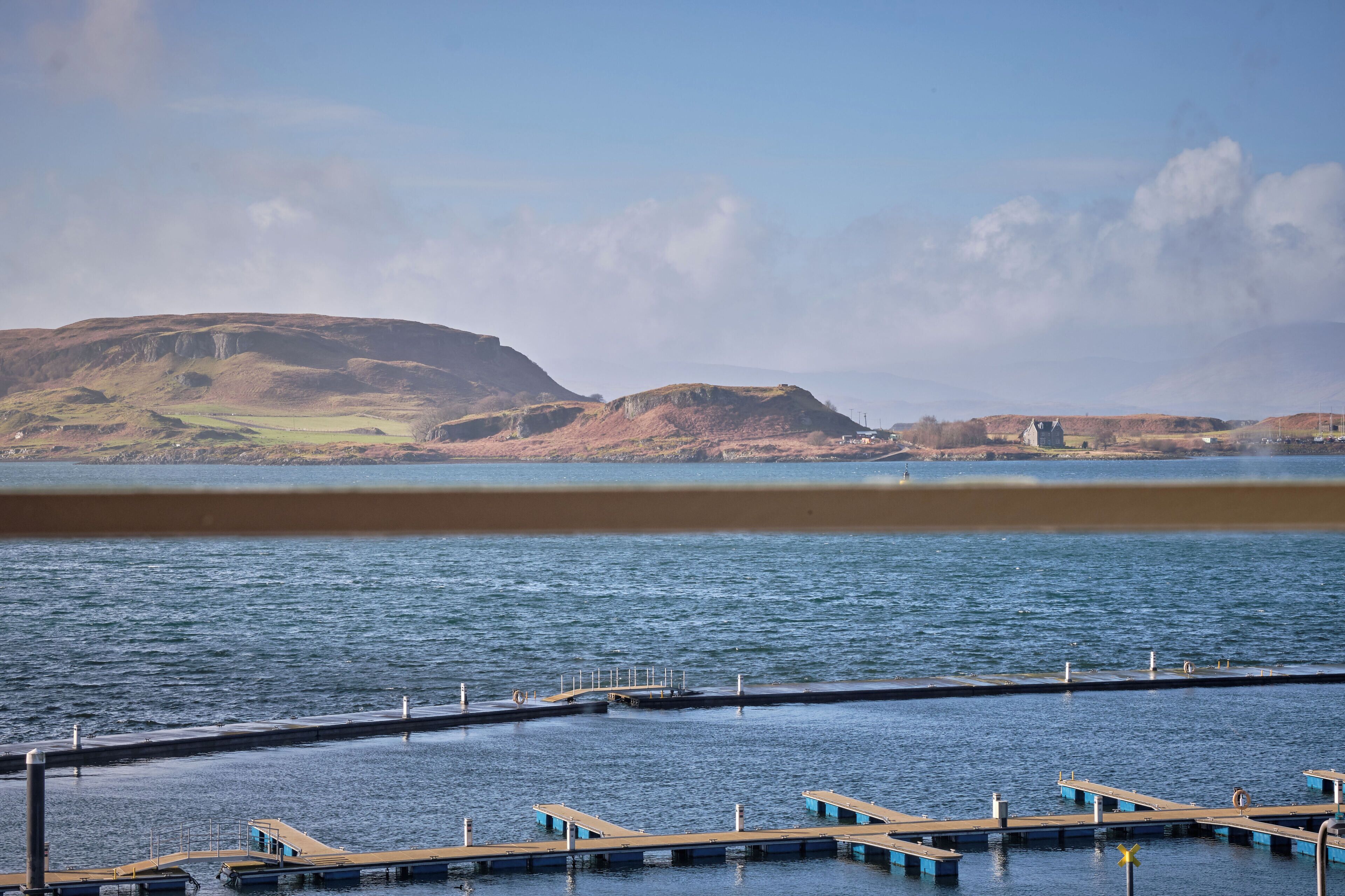 Un muelle frente al agua con vistas despejadas de las colinas circundantes y una superficie acuática tranquila.