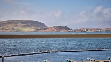 Un muelle frente al agua con vistas despejadas de las colinas circundantes y una superficie acuática tranquila.