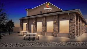 A Comfort Inn & Suites building with stone columns, large windows, and outdoor seating.