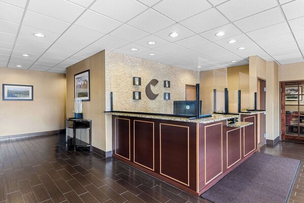A reception area with a wooden reception desk, a computer, and framed pictures on the wall.
