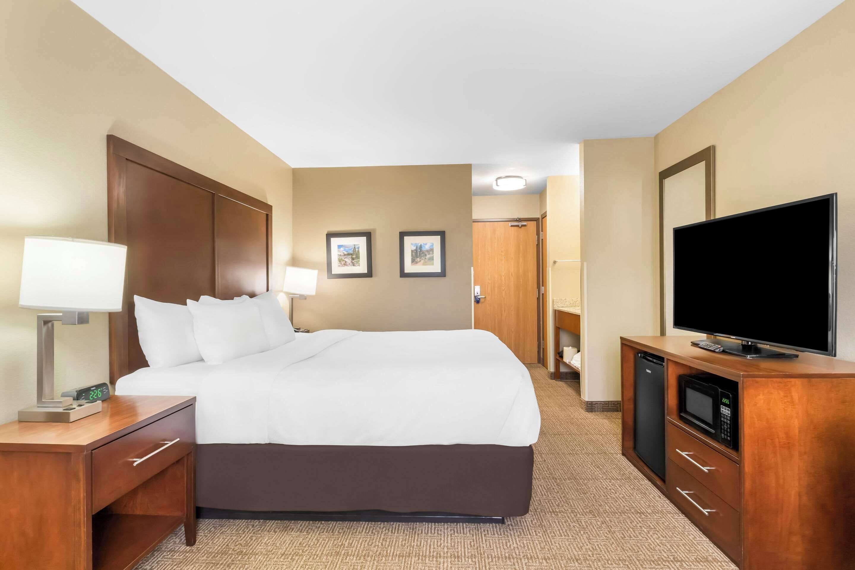 Een hotelkamer met een groot bed, een televisie, een magnetron en een kleine koelkast.