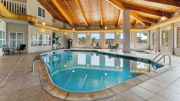 An indoor swimming pool with a wooden ceiling, clear windows, and a tiled floor.