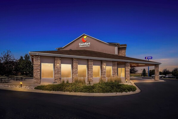 A Comfort Inn & Suites hotel with a modern design, featuring a prominent logo, large windows, and a well-lit entrance.