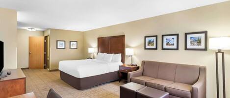 A hotel room with a bed, a sofa, a desk, and a TV.