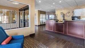 A hotel lobby with a reception desk, a blue armchair, and a patterned rug.