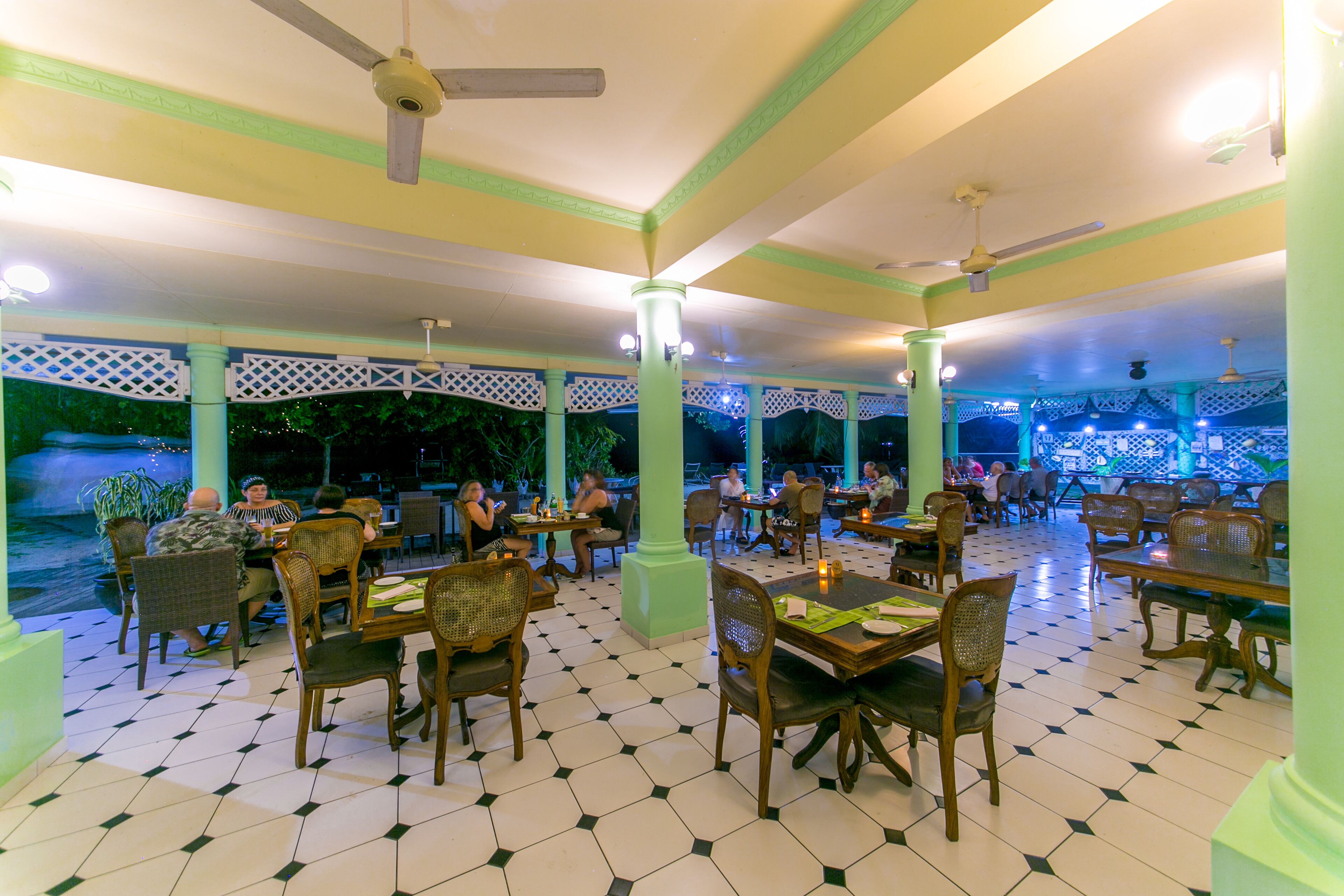 A restaurant with a tiled floor, wooden tables and chairs, and ceiling fans.