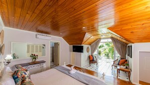 A spacious bedroom with a large bed, wooden ceiling, and a view of the outdoors. - Palm Beach Hotel (Praslin Island)
