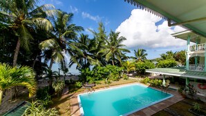 A rectangular swimming pool surrounded by palm trees and a covered area with a balcony. - Palm Beach Hotel (Praslin Island)
