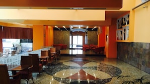 A lobby with a bar area, seating, and a patterned floor. - Hotel Celta (Zapopan)