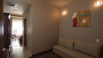 A room with a sofa, a small rug, and two wall-mounted light fixtures.