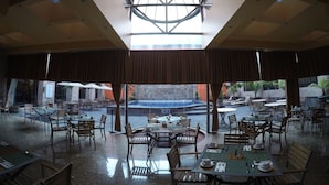 A spacious indoor dining area with high ceilings and large windows, featuring multiple tables and chairs. - Hotel Celta (Zapopan)