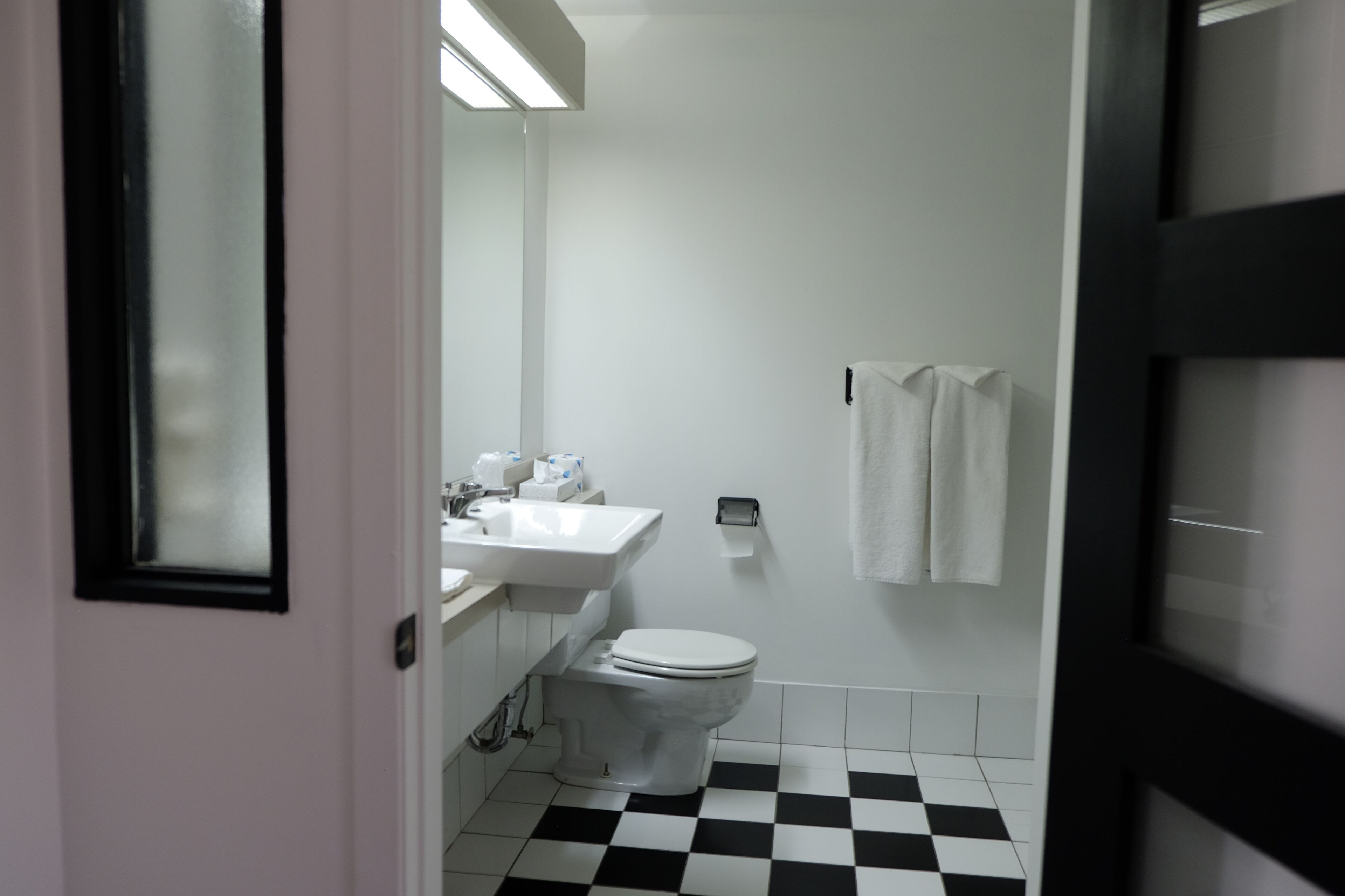 A bathroom with a white sink, toilet, and a checkered floor.