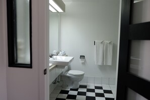 A bathroom with a white sink, toilet, and a checkered floor. - Auberge La Camarine (Beaupre)