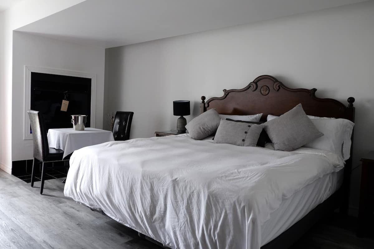 Un dormitorio con una cama grande, una mesita y una silla.