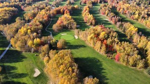 An aerial view of a golf course surrounded by autumn-colored trees. - Auberge La Camarine (Beaupre)