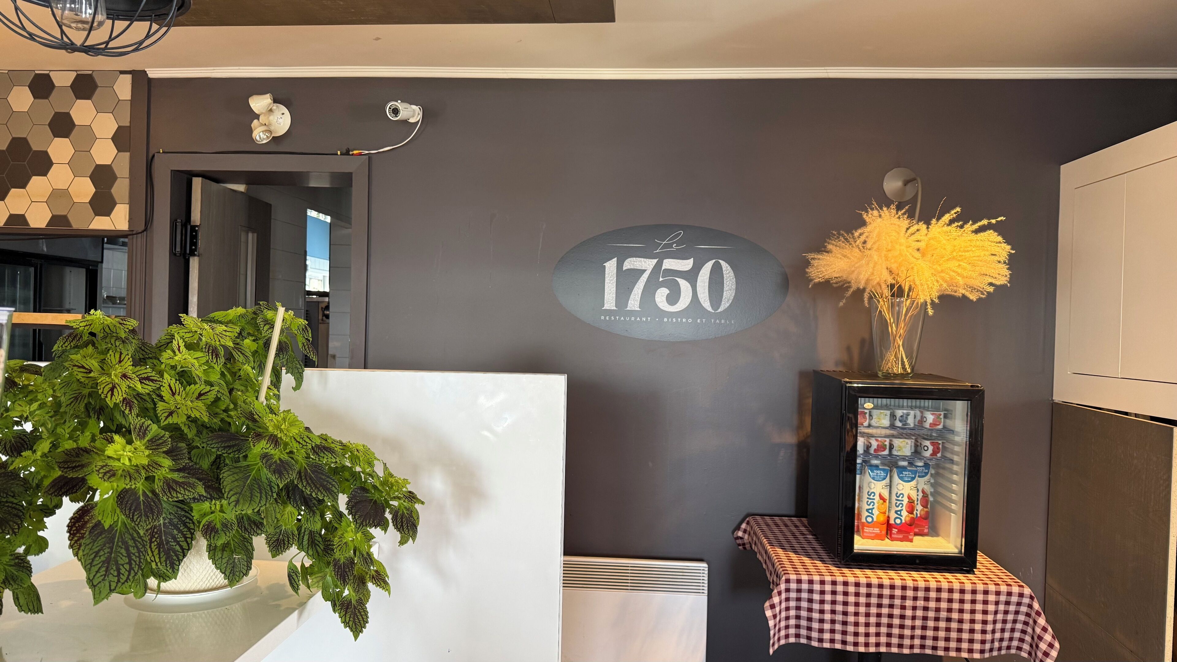 A modern interior with a checkered tablecloth, a framed picture of a product, and a wall-mounted sign reading "1750".