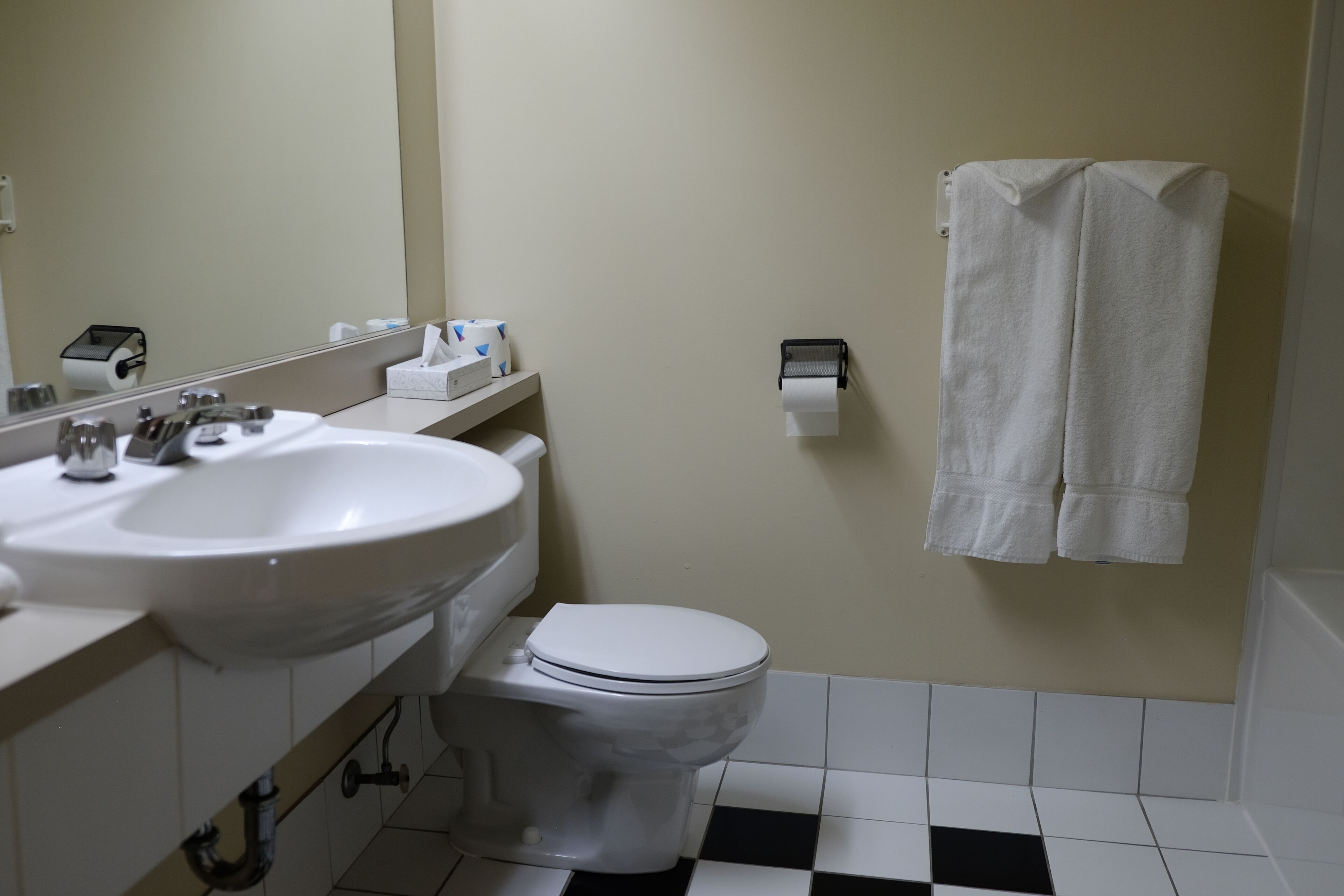 A bathroom with a white sink, toilet, and a towel hanging on the wall.