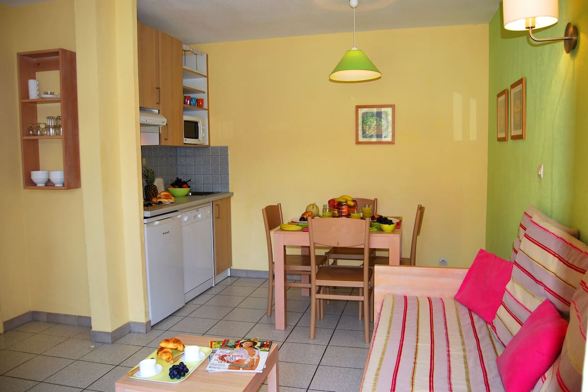 A compact living space with a dining area, kitchenette, and a sofa with striped cushions.