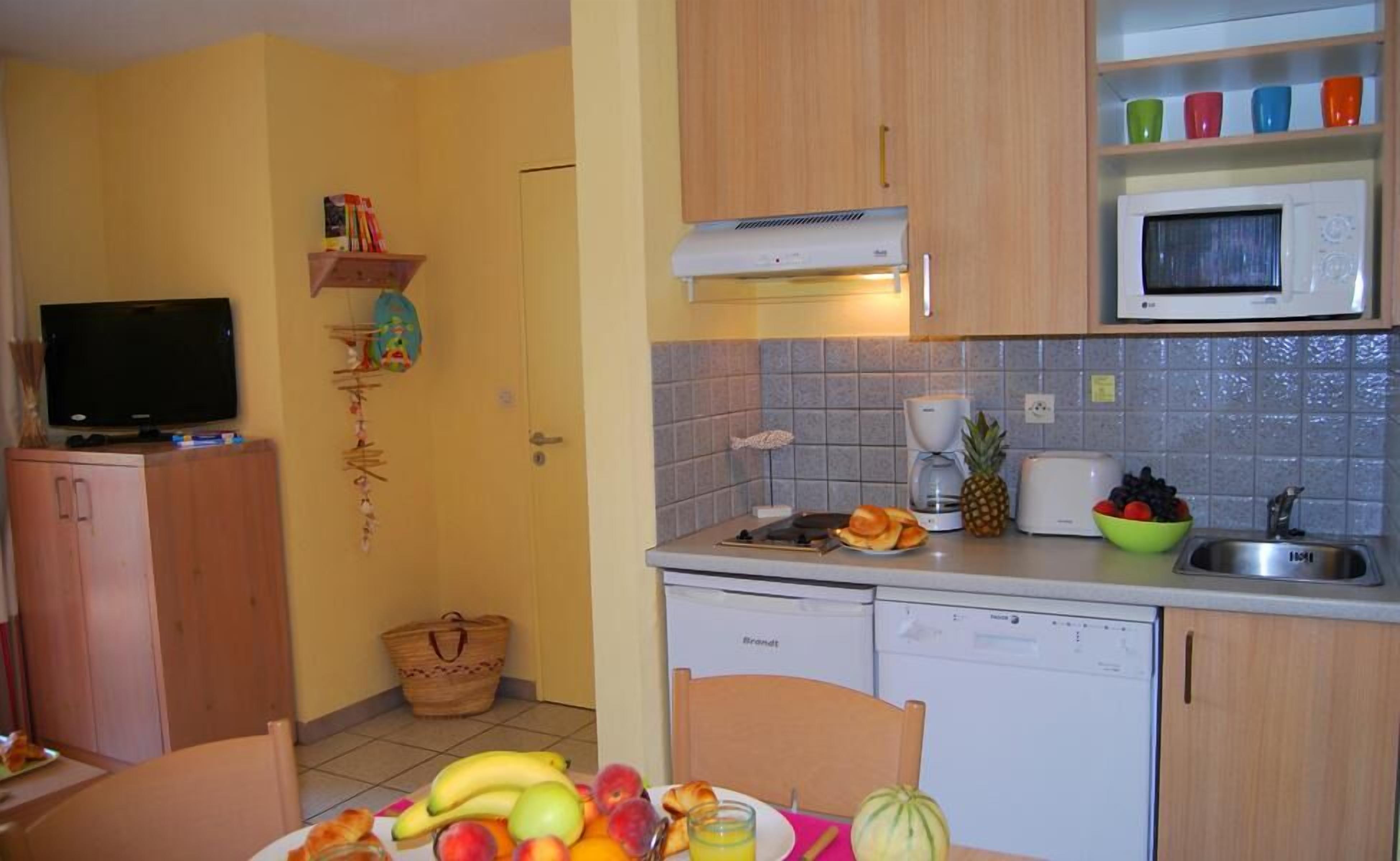 Eine kompakte Küche mit Mikrowelle, Toaster und einer kleinen Essecke.