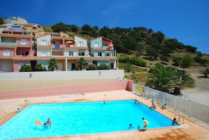 Relax by the hotel's rectangular pool, surrounded by lush greenery and a hillside backdrop.
