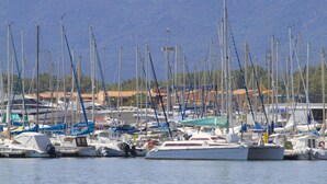 A marina with numerous sailboats docked, surrounded by buildings and mountains in the background. - Lagrange Vacances Les Pierres de Jade (Saint-Cyprien)