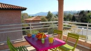 A balcony with a table set for two, featuring a fruit bowl, cups, and a glass of juice. - Lagrange Vacances Les Pierres de Jade (Saint-Cyprien)