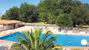A swimming pool surrounded by a fence, with people swimming and relaxing. - Lagrange Vacances Les Pierres de Jade (Saint-Cyprien)