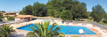 Une piscine entourée d’une clôture, où des gens nagent et se détendent.