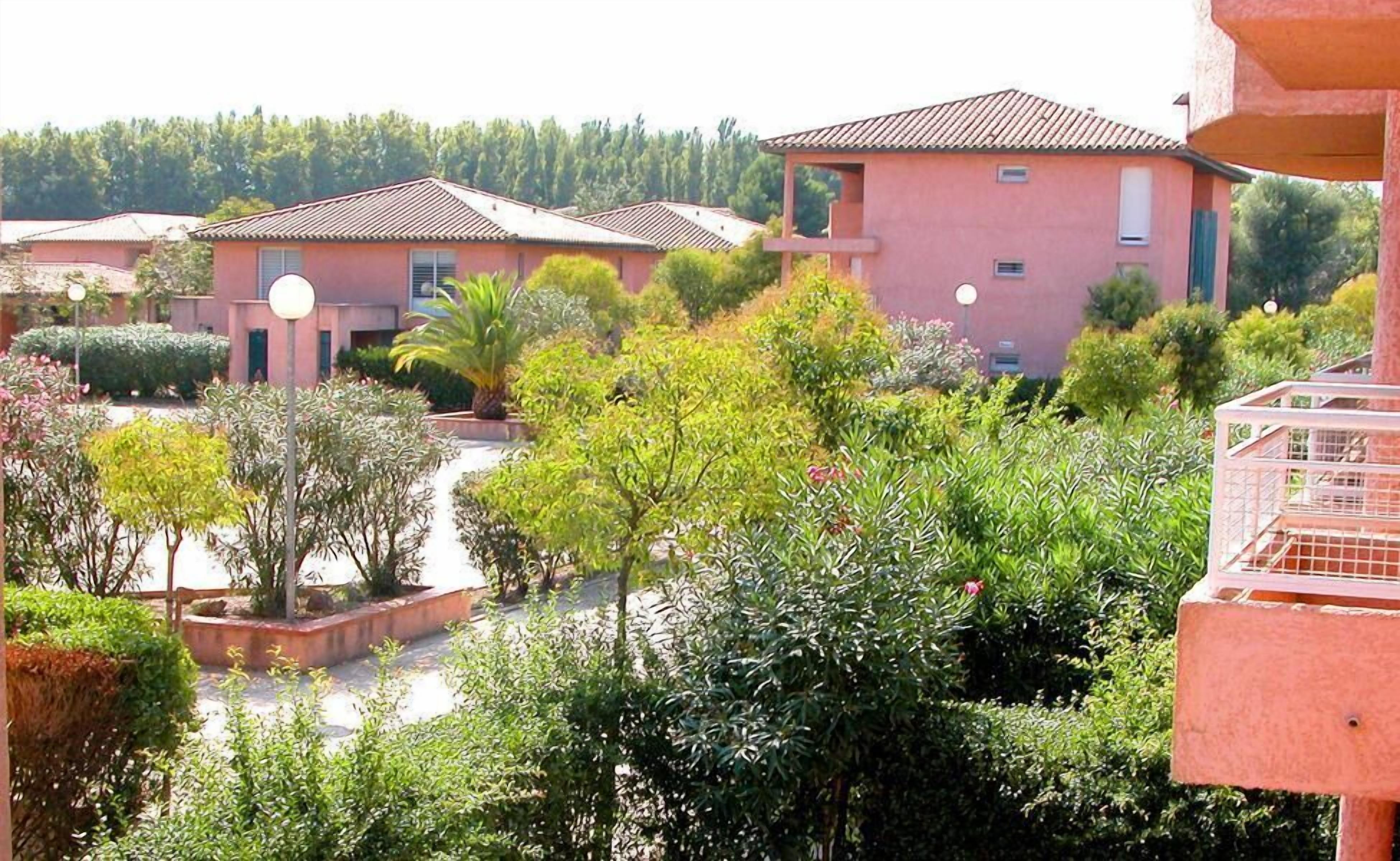 A residential area with multiple houses, a central courtyard with various plants, and a clear view of the surrounding landscape.