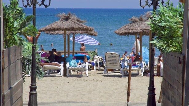 A beachside walkway leading to beach umbrellas and lounge chairs, with the sea in the background. - Lagrange Vacances Les Pierres de Jade (Saint-Cyprien)