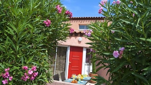A red door, a table with fruits and drinks, and a building with a tiled roof. - Lagrange Vacances Les Jardins de Neptune (Saint-Cyprien)