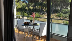 A balcony with a table set for two, a chair, and a potted plant. - Lagrange Vacances Les Jardins de Neptune (Saint-Cyprien)