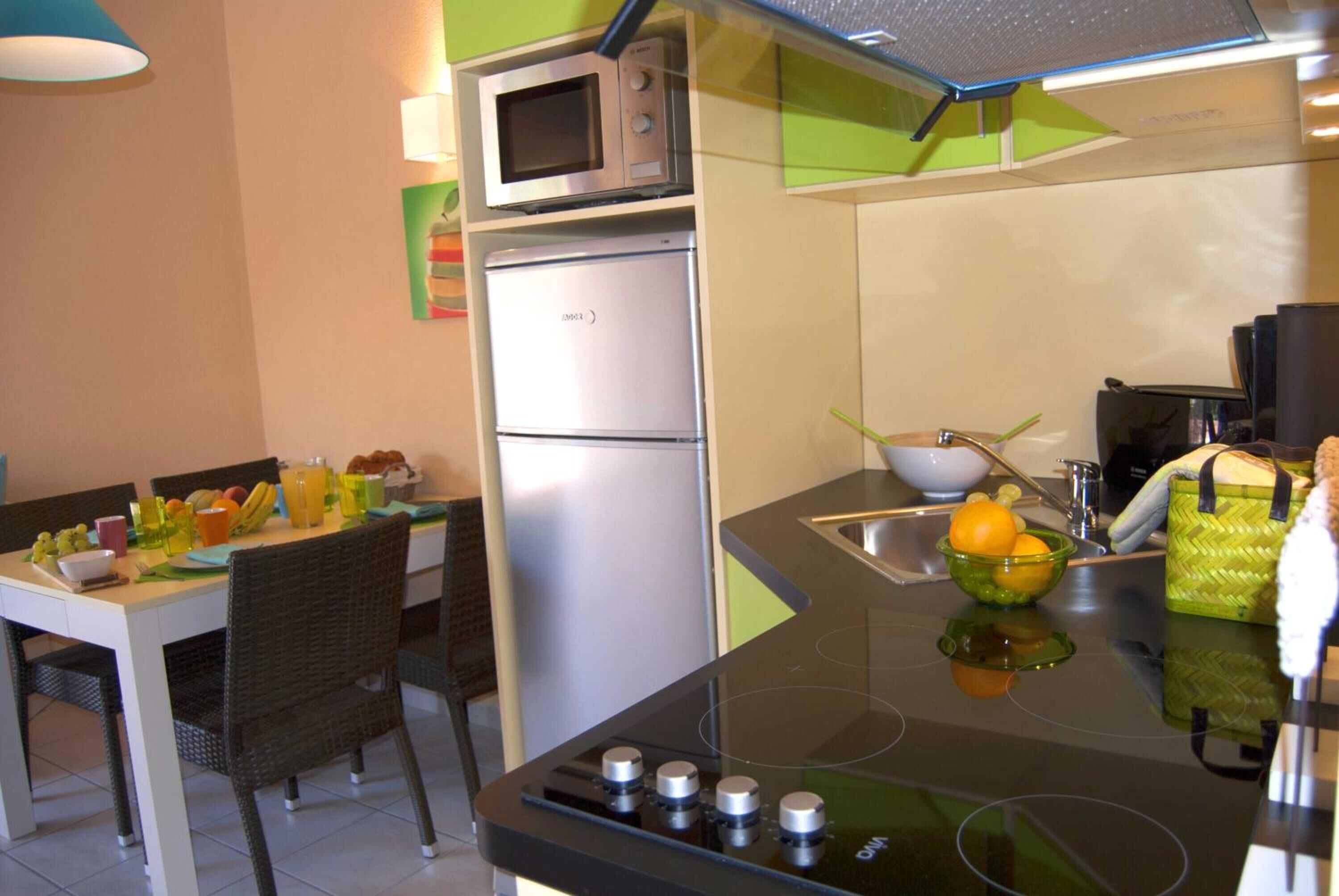 A compact kitchen with a microwave, refrigerator, and modern stove.