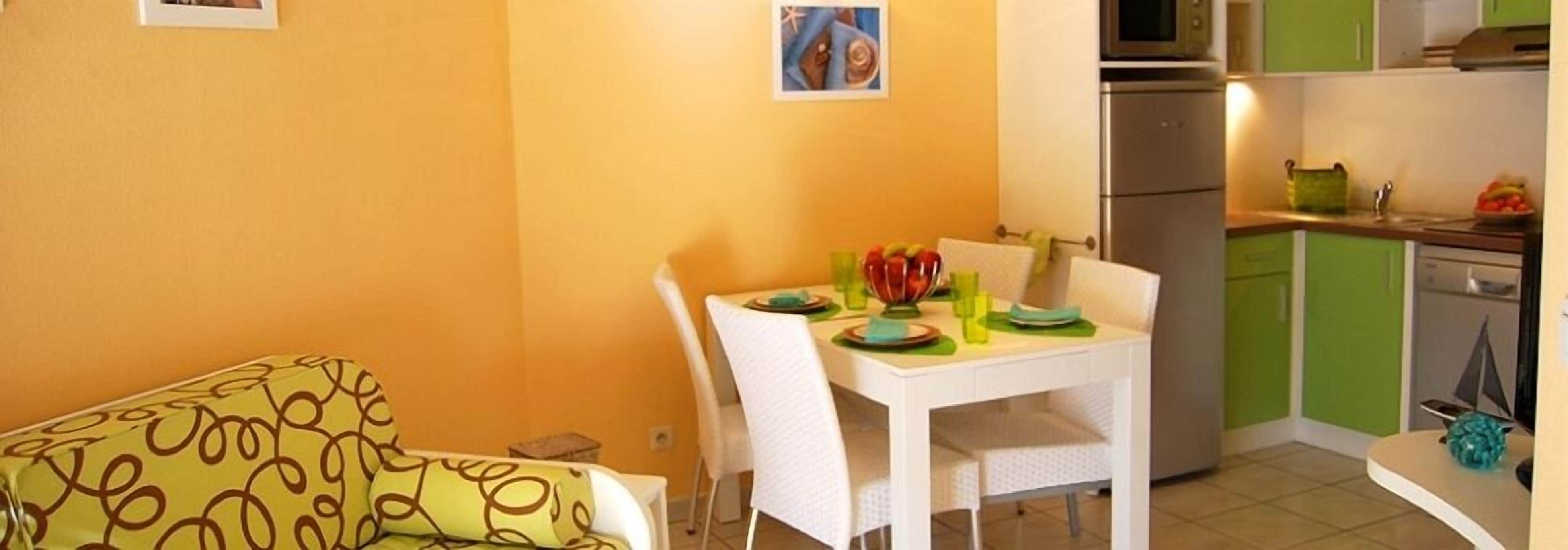 Una cocina compacta con una mesa de comedor preparada para cuatro personas, un microondas y un mueble verde.