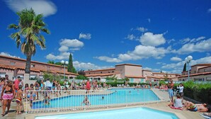 A swimming pool surrounded by a fence with people around it. - Lagrange Vacances Les Jardins de Neptune (Saint-Cyprien)