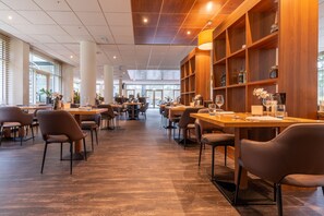 A spacious restaurant with high ceilings, wooden paneling, and a variety of seating arrangements. - Fletcher Hotel-Restaurant Beekbergen - Apeldoorn (Beekbergen)